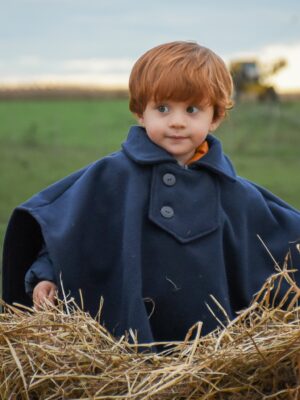 Poncho Tradición de Niño - Poncho de paño liso con cuello, solapa, cierre y dobladillo en bordes.